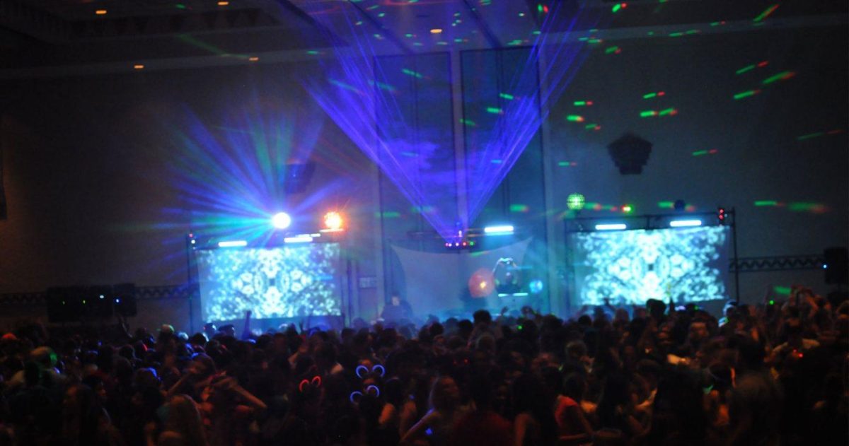 Fullt dansegulv foran DJ-en, med laserlys over scenen